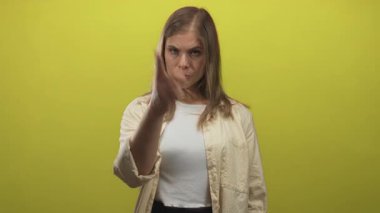 Sarı atölyeye beyaz atlet ve bej gömlek giyerek bakarken omuz hizasında kıvırcık saçlı sarışın genç bir kadın öfke uyarısı yapıyor..