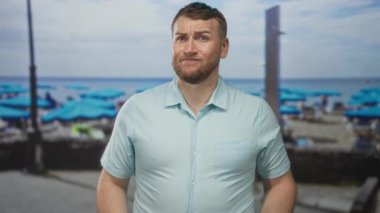 Mavi plaj şemsiyeleri, kum ve şezlonglar ile deniz kenarında duran endişeli yüzle el ele tutuşan adam belirsizlik.