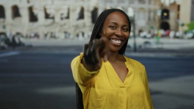 Roma ikonik kolezyumunun önünde gülümseyen ve işaret eden bir kadın Roma 'nın tarihi dış mekanında neşe ve bağlantı sergiliyor..