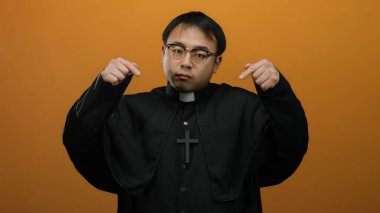 Turuncu arka planda siyah cüppeli Asyalı rahip hareketleri dini inancı ve kültürel çeşitliliği ruhani bir bağlamda vurguluyor..