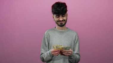 Norveç kronu banknotları tutan adam soyutlanmış pembe arka plana gülümsüyor. Finansal mutluluğu ve refahı gelişigüzel ifade ediyor..