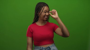 Kırmızı ekili üst göz kapağı çimdikleyen ve gözünün yanında küçük bir nokta tutarken, stüdyo yeşil ekranda şaşı bakan kadın; rahatsız küçük nesne.