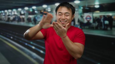 Kırmızı tişörtlü adam, Çin 'de çekilen bulanık tren yolunun önündeki canlı tren istasyonunda gülümseyen para işareti yapıyor..