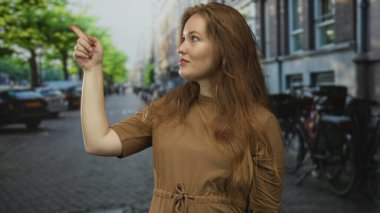 Kahverengi gömlekli kadın, hareketli bir şehir caddesinde inşaat yapmaya işaret ediyor; berraklık güveni görüşü.