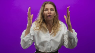 Eller havada, avuçlar mor stüdyoda beyaz gömlek ve kemer giymiş bir kadın bağırıyor. Öfke..