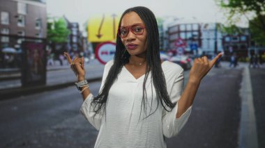 Kırmızı gözlüklü kadın trafik işaretleri ve binaları bulanık bir caddede hem dışa hem de dışarı işaret ediyor..