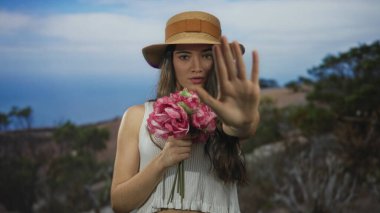 Saman şapkalı, elinde pembe çiçekler olan genç İspanyol kadın Green Park 'ta el hareketini durdurmak için kaldırıldı. Sınır belirleme ve çözüm.
