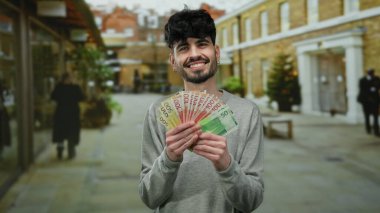 Bir şehir caddesinde Norveçli kronu elinde tutan gülümseyen adam, gün içinde şehir içinde büyüleyici bir ifadeyle renkli paralar sergiliyor..