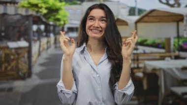 Güneşli bir restoran terasında, tahta sandalyeli ve saksı bitkileriyle taş bir geçitte dua eden bir kadın, umut verici bir beklenti içinde..