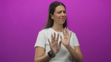 Genç esmer kadın stüdyoda avuçlarını öne doğru itiyor. Kırmızı arka planda beyaz tişört giyiyor. Tiksinti reddediliyor..