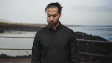 Dostum, genç Arap sakallı ve saçları bağlı, siyah gömlekli kaşları çatık ve kayalık sahildeki korkuluklara bakıyor; düşüncelere dalmış yalnızlık.