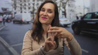 Genç İspanyol kadın şehir caddesinde parmaklarıyla hashtag hareketi yapıyor; trend bağlantısı etkileşimi.