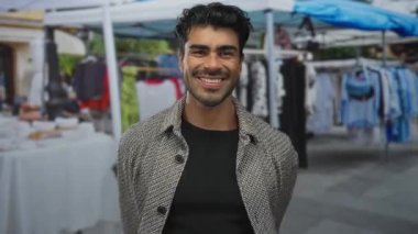 Yoğun şehir caddesindeki sokak pazarında canlı hediyelik eşya tezgahları arasında ceketli adam kol esnetiyor; kendine güven.