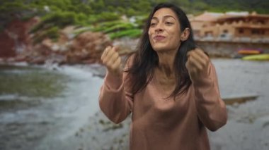 Kadın, sahil evleri ve sahil kenarındaki sahil yolunda kapalı gözlerle yumruklarını sıkıyor ve gülüyor; kişisel zafer.