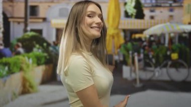 Şehir terasında renkli şemsiyeler ve açık havada oturan, canlı şehir yaşamını gözler önüne seren, yemyeşil ve modern mimariyle çevrili bir kadın..