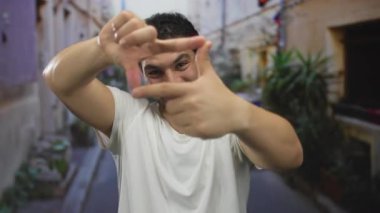 Genç Hispanik adam canlı mor bir şehir caddesinde elleri ile sokak görünümünü çerçeveler; ilham yaratıcı hayal gücü.