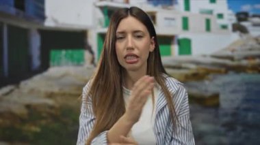 Çizgili gömlekli kadın kollarını kavuşturur ve kayalık sahilde dalgaların üzerinde gözlerini kapatır..