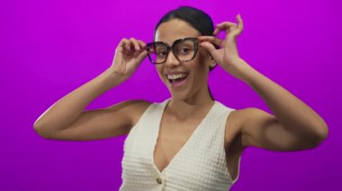 Gözlüklü İspanyol kadın canlı pembe bir arka plan, pozitiflik ve kendine güven konusunda onay veriyor..