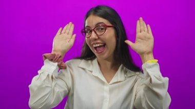 Kırmızı gözlüklü genç bir kadın ve zarif beyaz bir bluz bir stüdyoda elleri ile yüzünü örtüyor..