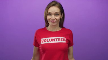 Mor stüdyodaki kırmızı gömleğin üzerinde gönüllü logosu olduğunu gösteren beyaz bir kadın..