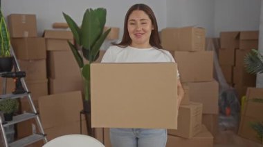 Taşınma gününden sonra etrafını erzak paketleriyle saran ve kutuları bir binaya istifleyen bir kadın..