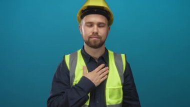 Göğsünde sarı bir şapka ve yelek giyen bir tamirci. Stüdyoda. Samimi ve sessiz bir minnettarlık..