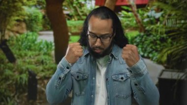 İnsan, orman parkı yolunda yere bakan bakışlarla yumruklarını sıkar. Kot ceket görünür. Kararlılık direnci..