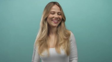 Uzun sarı saçlı ve kapalı gözlü bir kadın fotoğraf stüdyosunda dudaklarını büzüştürerek öpüşüyor..