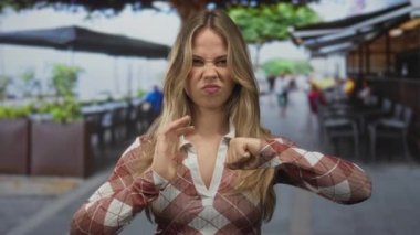 Sarışın kadın sabah koşuşturması sırasında kaldırımda ellerini sıkıca kavrıyor. Öfke bunalımı..