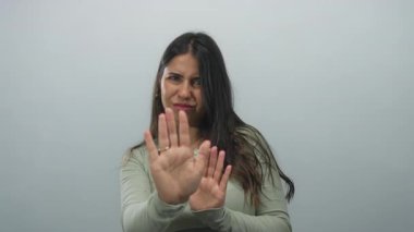 İzole edilmiş beyaz arkaplan karşısında el kol hareketi yapan, reddeden ya da inkar eden genç İspanyol kadın reddedilme duygusunu ifade ediyor..