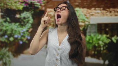 Gözlüklü genç İspanyol kadın dışarıdaki avluya doğru işaret ediyor. Heyecan..