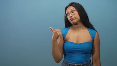 Genç kadın stüdyoda gözlük ve mavi kolsuz bluz ve kot pantolon giyerek parmak uçlarına basıyor..