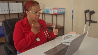 Steteskoplu doktor göğsünü sıkıyor ve teletıp çağrısı sırasında dizüstü bilgisayara doğru hareket ediyor..