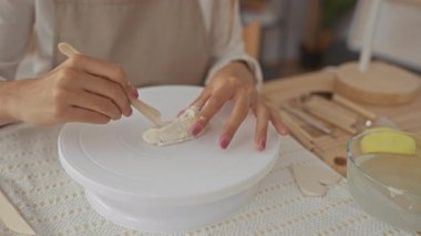 Stüdyoda çömlek çarkında kil şekillendiren genç sarışın kadın elleri; yaratıcılık odaklı zanaat sakinliği.