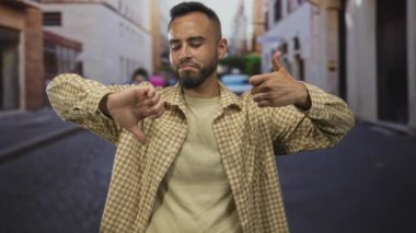 Man giving thumbs up and thumbs down on street with visible hands and thoughtful expression; ambivalence decision.