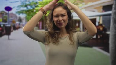 Genç İspanyol kadın, açık hava restoranının terasında çatı jesti oluşturmak için el kaldırıyor..