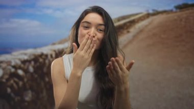 İki eliyle öpüşen bir kadın açık gökyüzünün altında taş duvarla kaldırılır. Mutluluk bağlantısı..