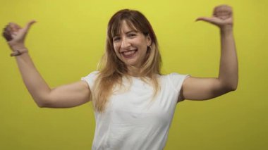 Sarı stüdyoda beyaz tişört giyen ve gözleri kapalı gülen bir kadın..