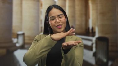 Genç Latin kökenli, açık havada yaşayan, şehir bağlamında para gösteren bir şehirde kadın el hareketi yapıyor..