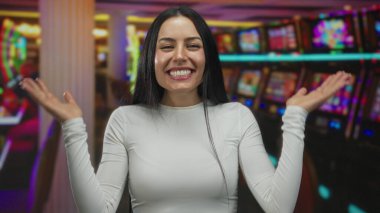 Kumarhanede etrafını saran kumar makineleriyle gülümseyen bir kadın canlı bir iç mekan ortamında heyecanını ifade ediyor..