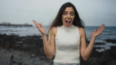 Kumlu kayalık sahil şeridinde ağzı kapalı bir kadın kolsuz bluz giyiyor; beklenmedik bir şok..