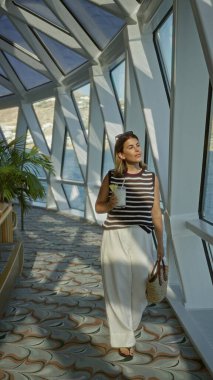 Bir binadaki yolcu gemisinin camlarında samandan kokteyl yudumlayan bir kadın; dinlenme tatili.