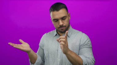 Genç ispanyol adam avuç içini açar ve reddedildiği için mor stüdyoda işaret parmağını kaldırır..