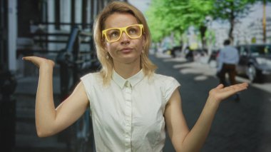 Sarı gözlüklü kadın, park halindeki arabaların yanındaki kaldırıma başını kaldırıyor..