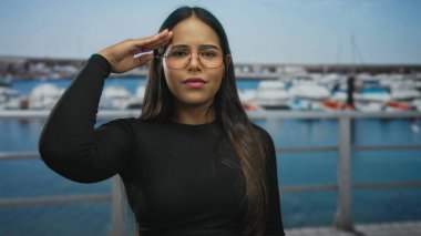 Neşeli bir limanın önünde, güneşli bir yere demirlemiş, kararlı ve genç bir ruhu olduğunu belirten, güven dolu bir şekilde selamlayan bir kadın..