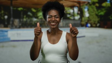 Açık hava parkında gülümseyen bir kadın güneşli bir günde mutluluk ve pozitiflik sergiliyor..