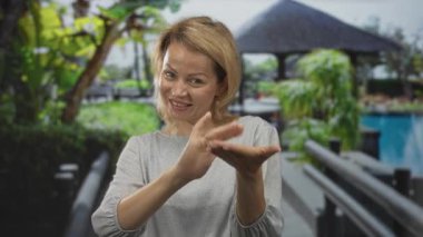 Bir binada para harcamak için parmaklarını ovuşturan genç sarışın kadın, zenginliğe düşkünlük arzusu.