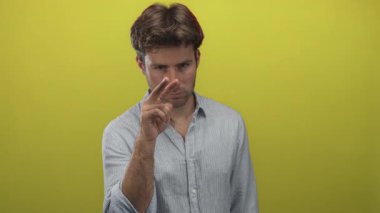 Stüdyoda, çizgili gömlek giyen ve dik dik bakan yeşil arka planda kameraya işaret eden adam, özenli bir konsantrasyon.