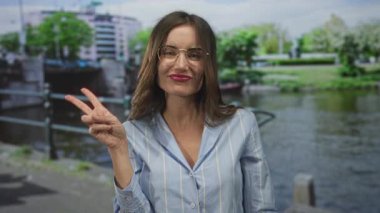 Gözlüklü genç kadın zafer için el ele tutuşuyor. Kanal suyuna işaret koy. Neşe kutlaması..