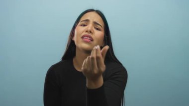 Bir kadın, arka planda genç bir Latin 'in mavi bir duvara karşı elini tutup yalvararak poz veriyor..